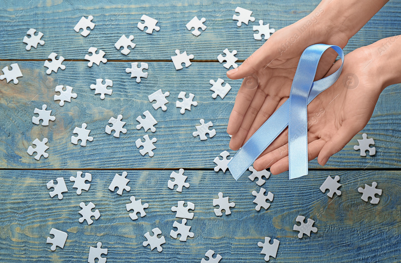 Photo of Woman with blue ribbon on wooden background. Autism concept