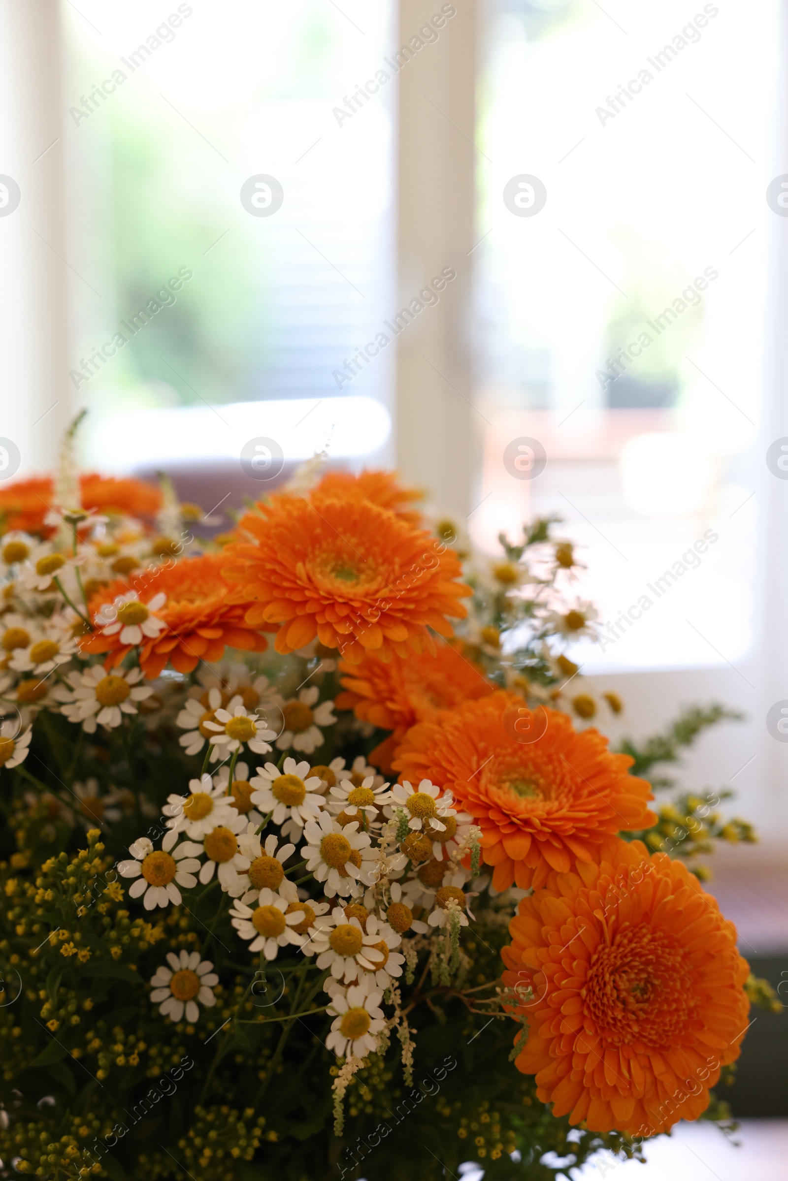 Photo of Fresh bouquet of chamomile and calendula flowers indoors, closeup