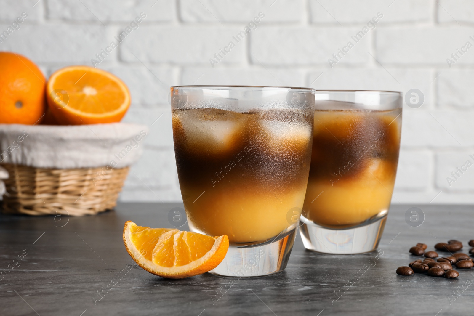 Photo of Tasty refreshing drink with coffee and orange juice on grey marble table