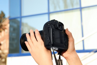Female photographer holding professional camera outdoors, closeup