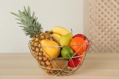 Photo of Fresh ripe fruits in metal bowl on wooden table
