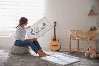 Photo of Decorator with picture on pouf in baby room. Interior design