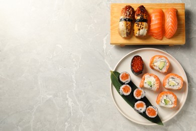Photo of Delicious sushi rolls on light grey marble table, flat lay. Space for text