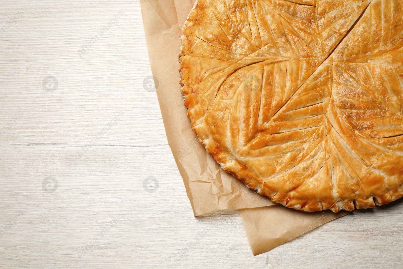 Photo of Traditional galette des rois on white wooden table, top view. Space for text
