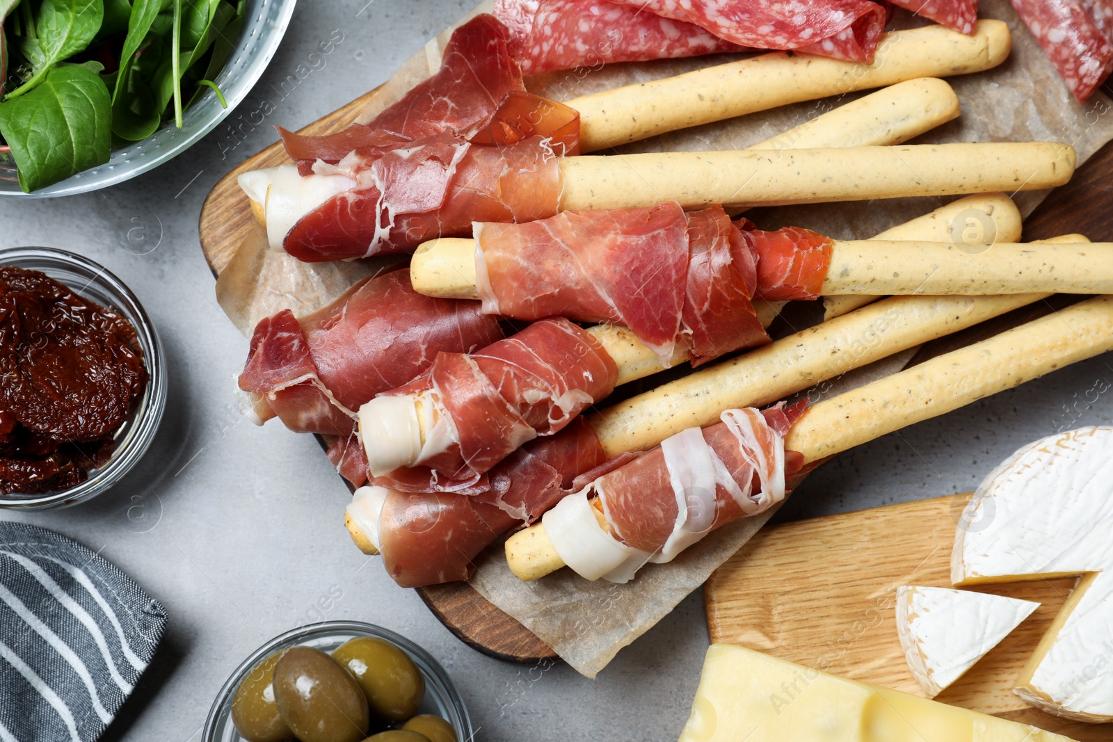 Photo of Tasty prosciutto served on light grey table, flat lay