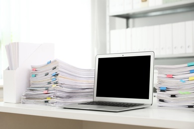 Laptop and documents on desk in office. Space for text