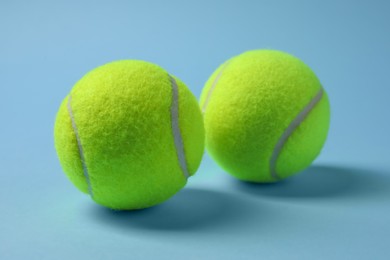 Photo of Two tennis balls on light blue background, closeup
