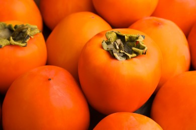 Pile of delicious ripe juicy persimmons as background, closeup