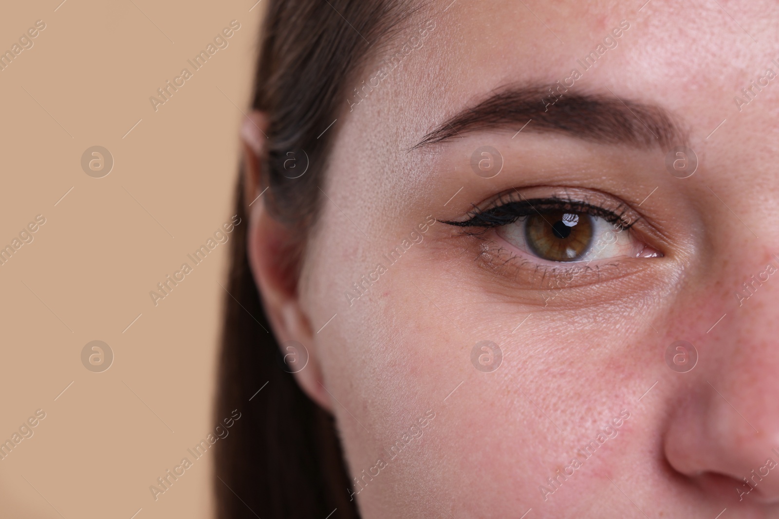 Photo of Closeup view of woman with beautiful hazel eyes on beige background. Space for text