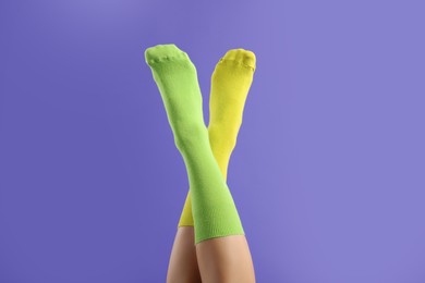 Woman in different stylish socks on violet background, closeup