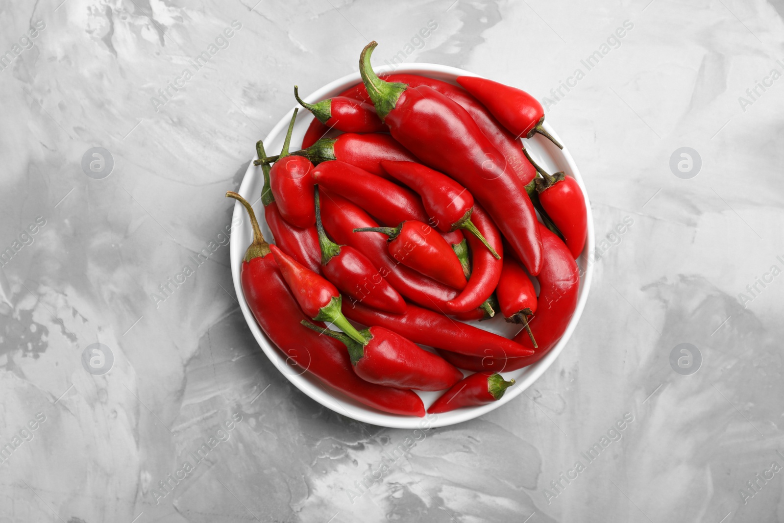 Photo of Bowl with red chili peppers on table, top view