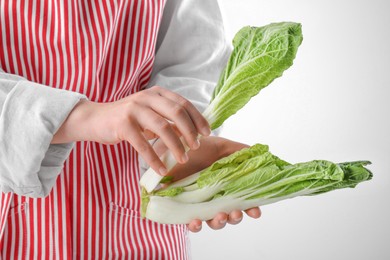 Photo of Woman with fresh cabbage on light grey background, closeup