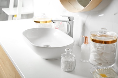 Photo of Cotton swabs and pads near sink on white countertop