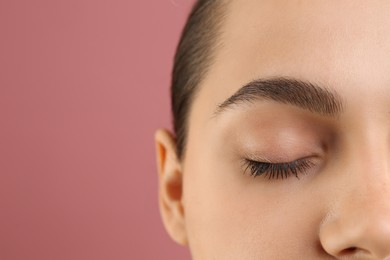 Young woman with perfect eyebrows on pink background, closeup. Space for text