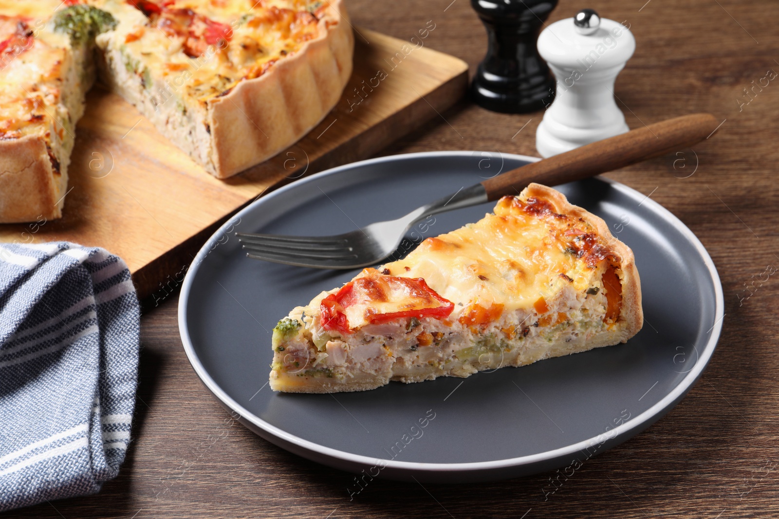 Photo of Tasty quiche with chicken, vegetables and cheese served on wooden table, closeup