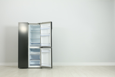 Photo of Modern refrigerator near light grey wall. space for text