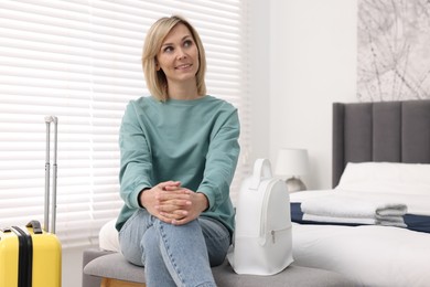 Photo of Smiling guest with backpack and suitcase in stylish hotel room