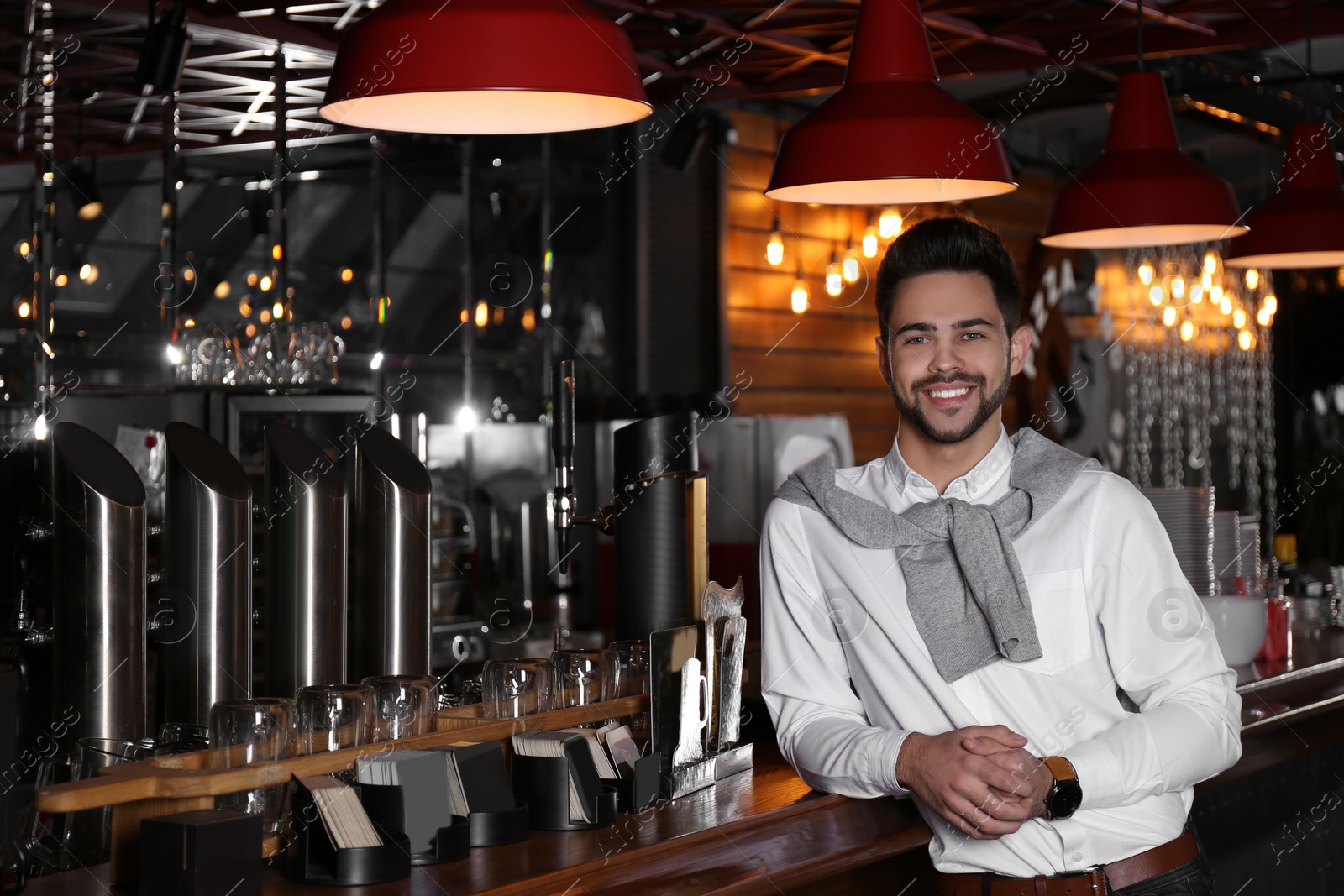 Photo of Young business owner standing near counter in his cafe