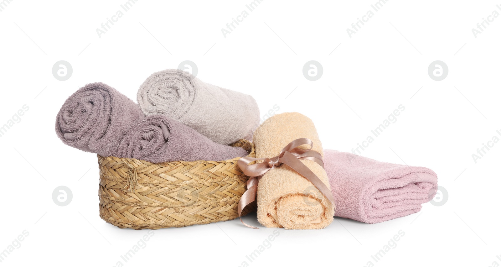 Photo of Wicker basket and rolled bath towels on white background