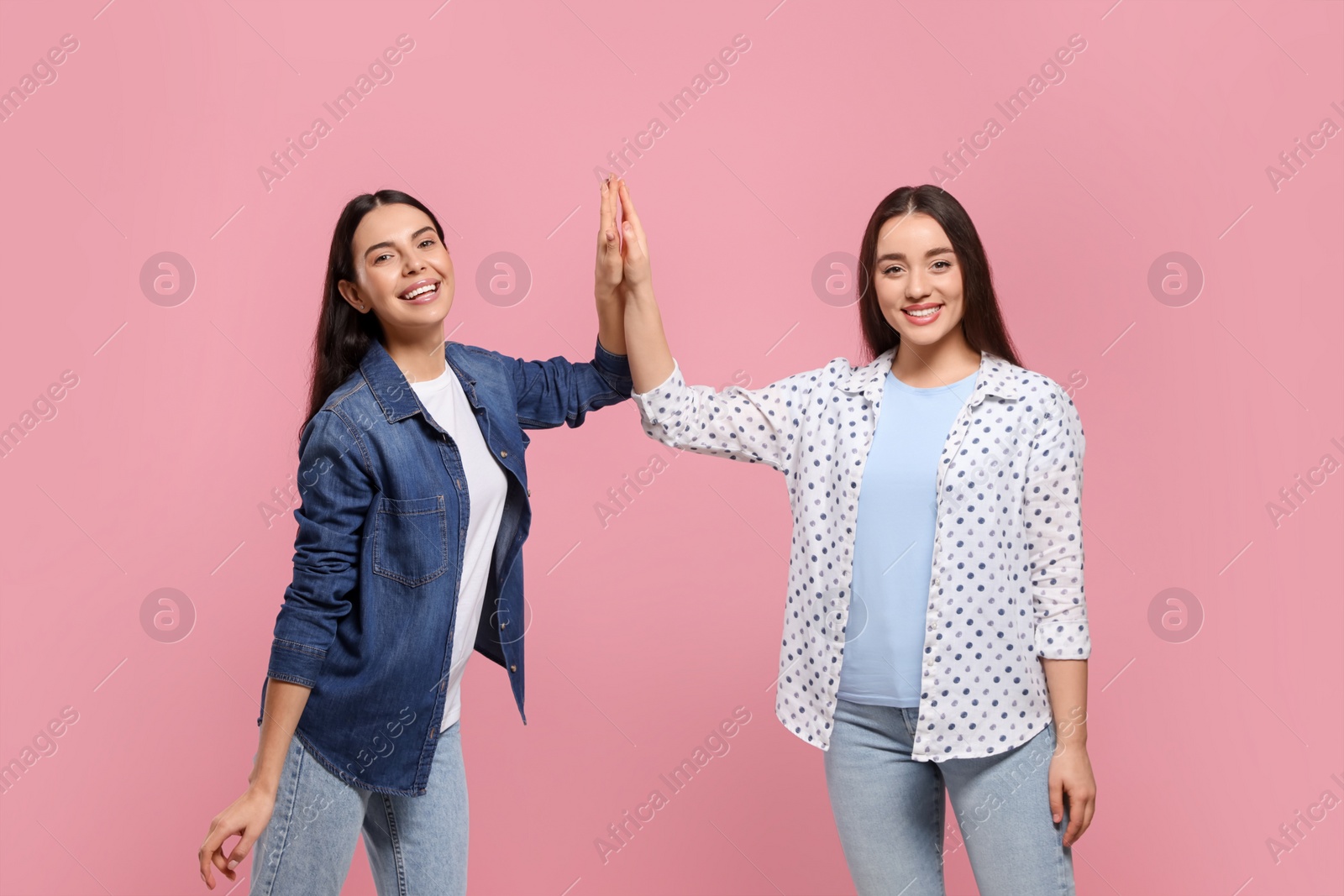 Photo of Women giving high five on pink background