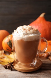 Photo of Glass cup with tasty pumpkin spice latte on wooden table