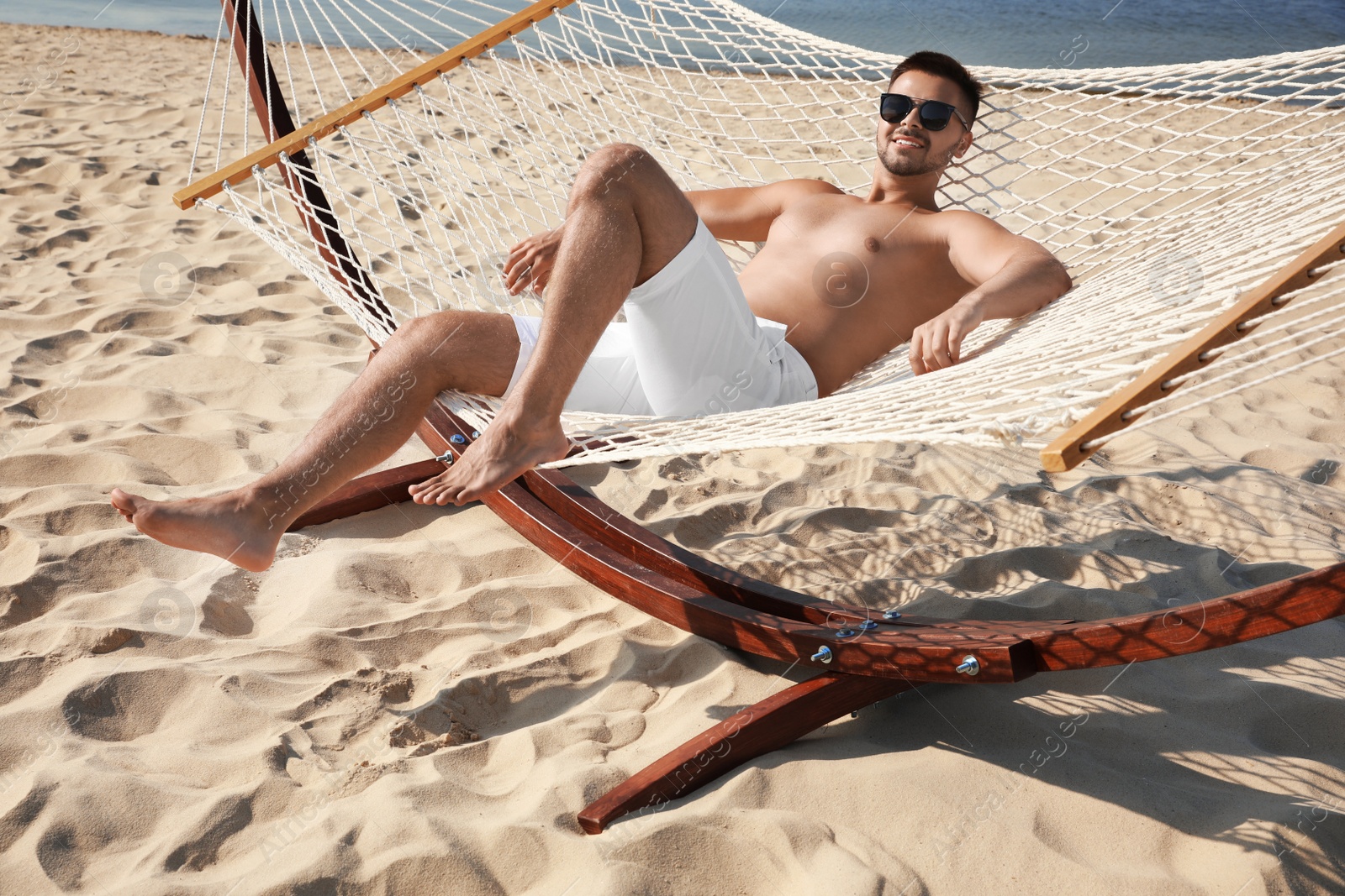 Photo of Young man relaxing in hammock on beach