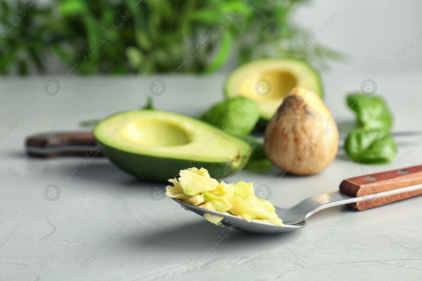 Photo of Spoon with tasty avocado pulp on table