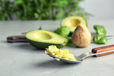 Spoon with tasty avocado pulp on table