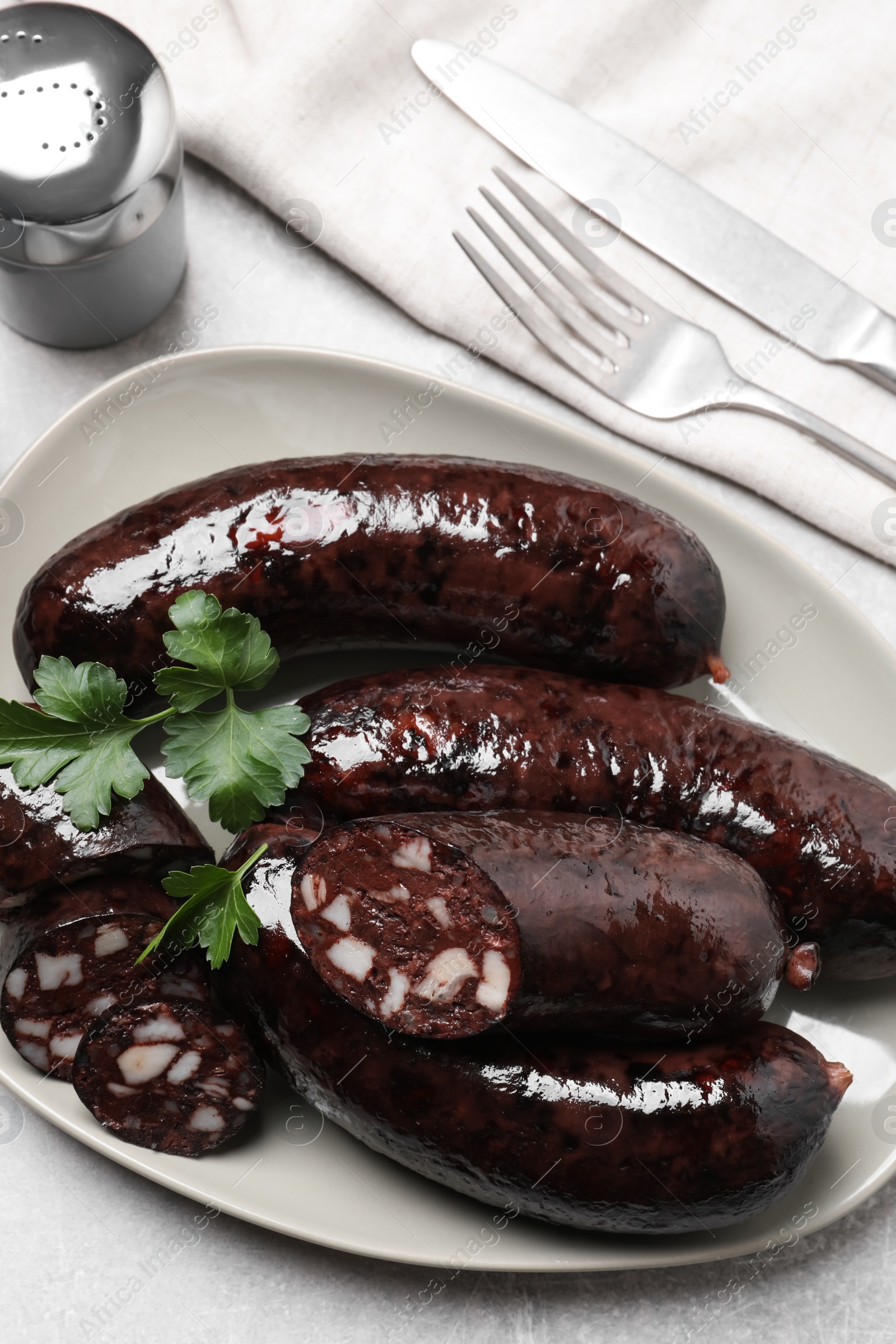 Photo of Tasty blood sausages with parsley served on light grey table, flat lay