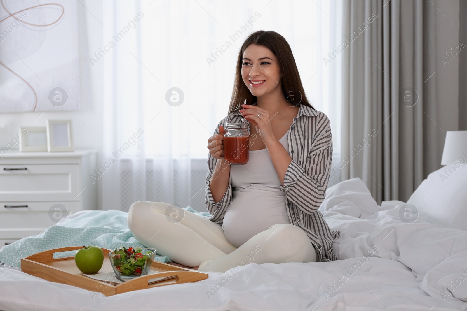 Photo of Pregnant woman eating breakfast on bed at home. Healthy diet