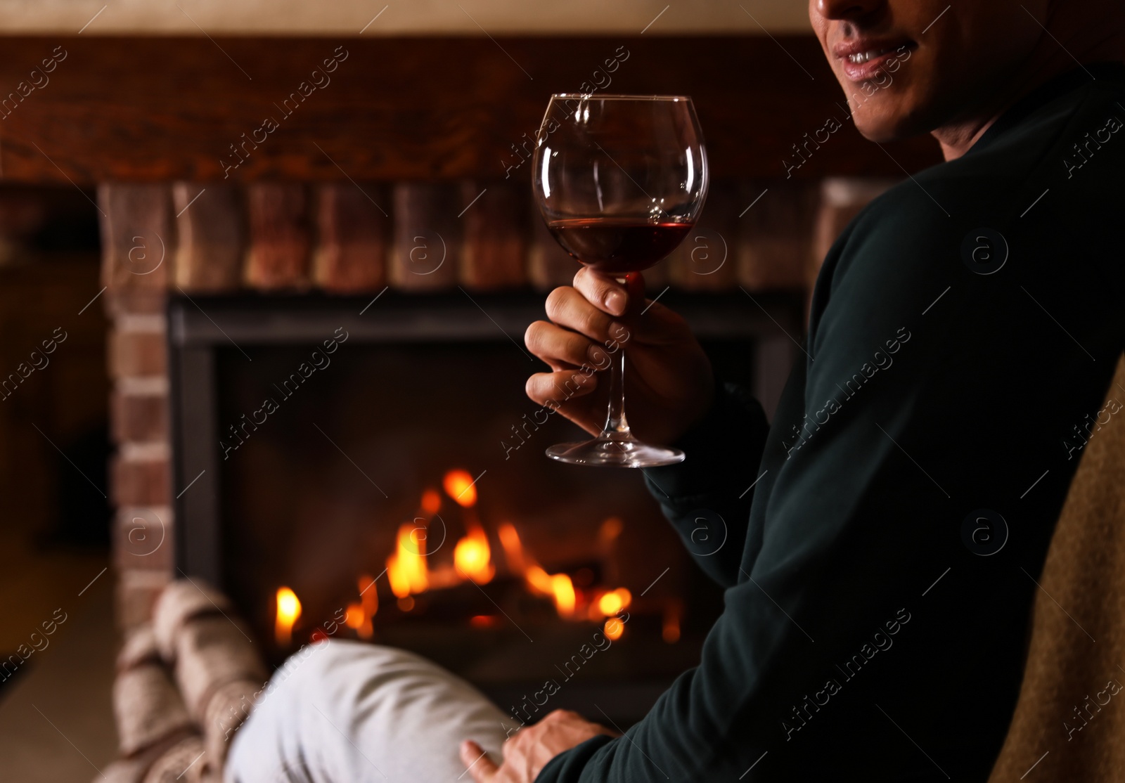 Photo of Man with glass of wine near fireplace at home, closeup