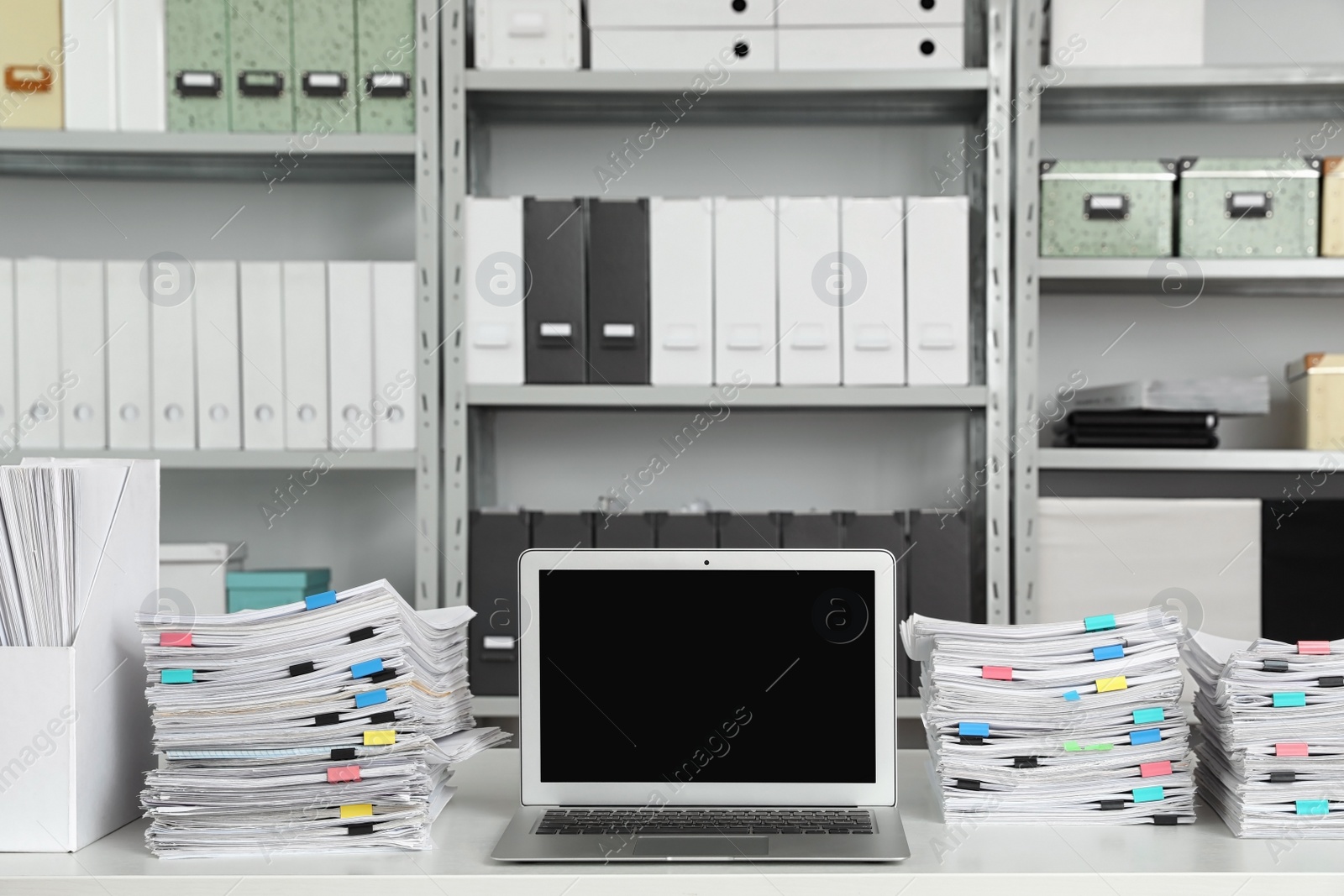 Photo of Laptop and documents on desk in office. Space for text