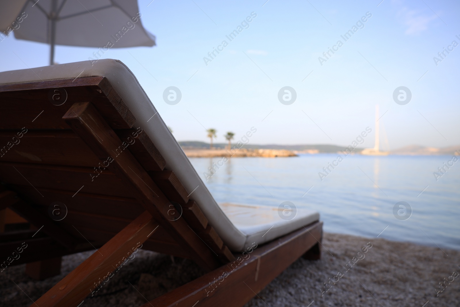 Photo of Beautiful view of seashore with sunbed on sunny day, closeup