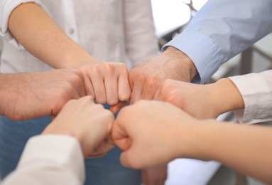 Photo of People holding fists together in office, closeup