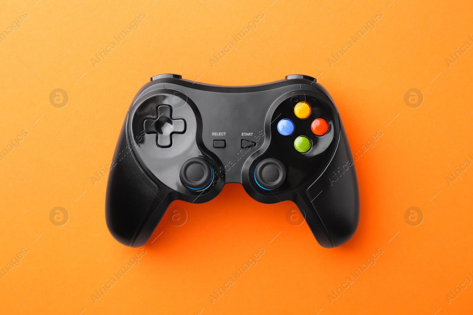 Photo of Wireless game controller on orange background, top view