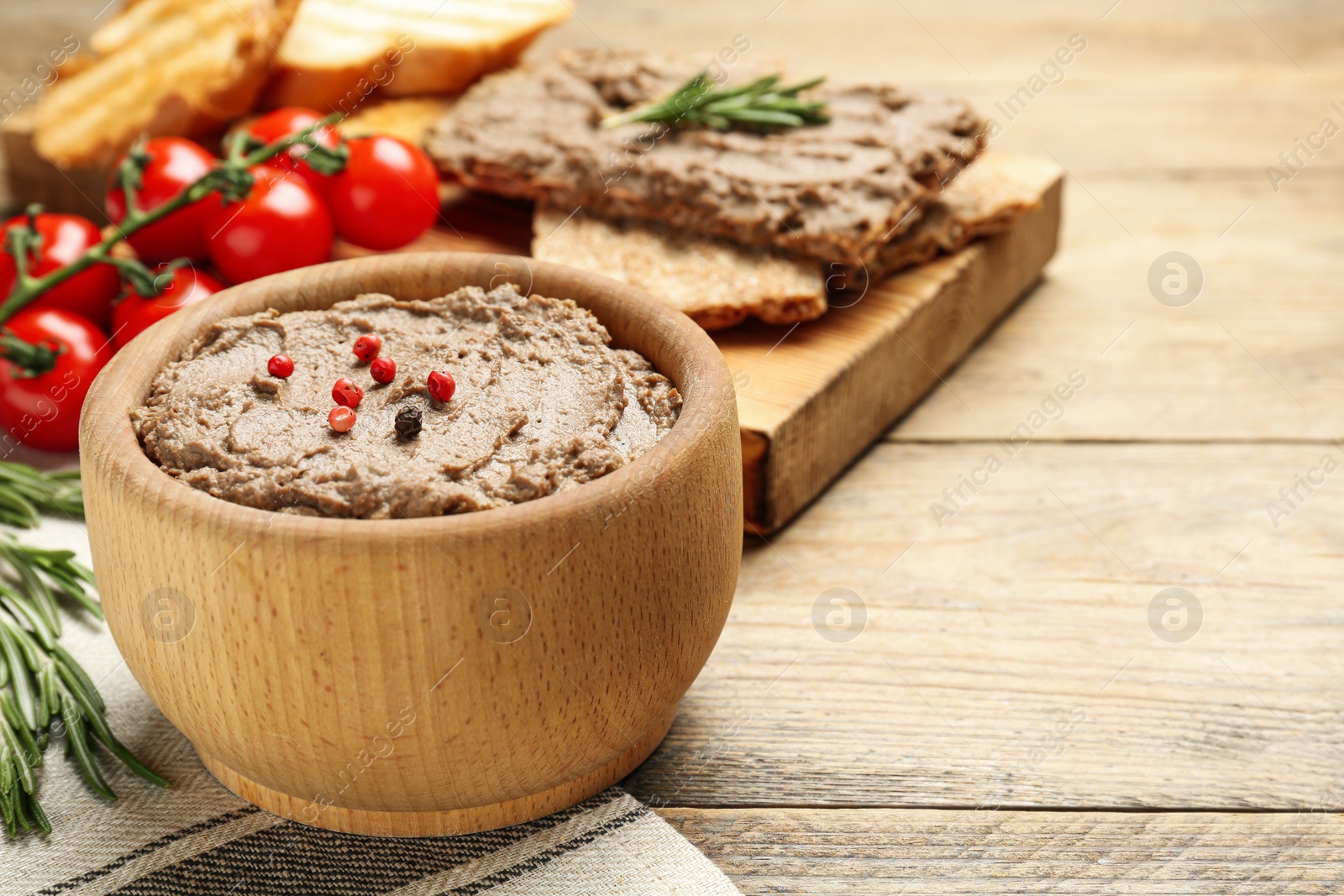 Photo of Tasty liver pate with pepper on wooden table, space for text