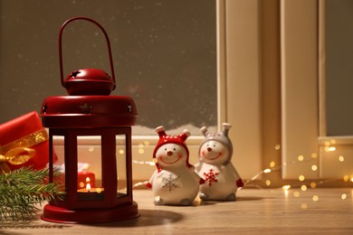 Photo of Red Christmas lantern with burning candle and festive decor on window sill indoors. Space for text