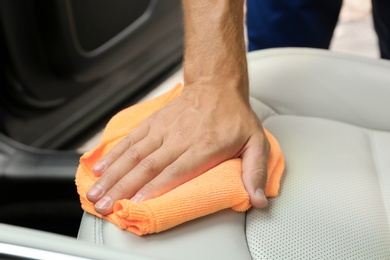 Photo of Man washing car seat with rag, closeup