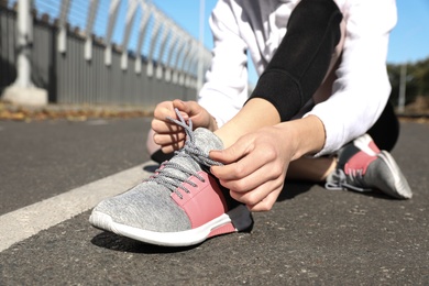 Photo of Sporty woman tying shoelaces before running at stadium