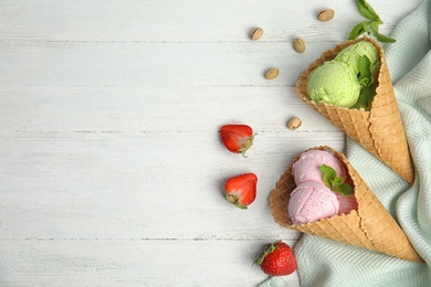 Photo of Flat lay composition with delicious ice creams in waffle cones on wooden table, space for text