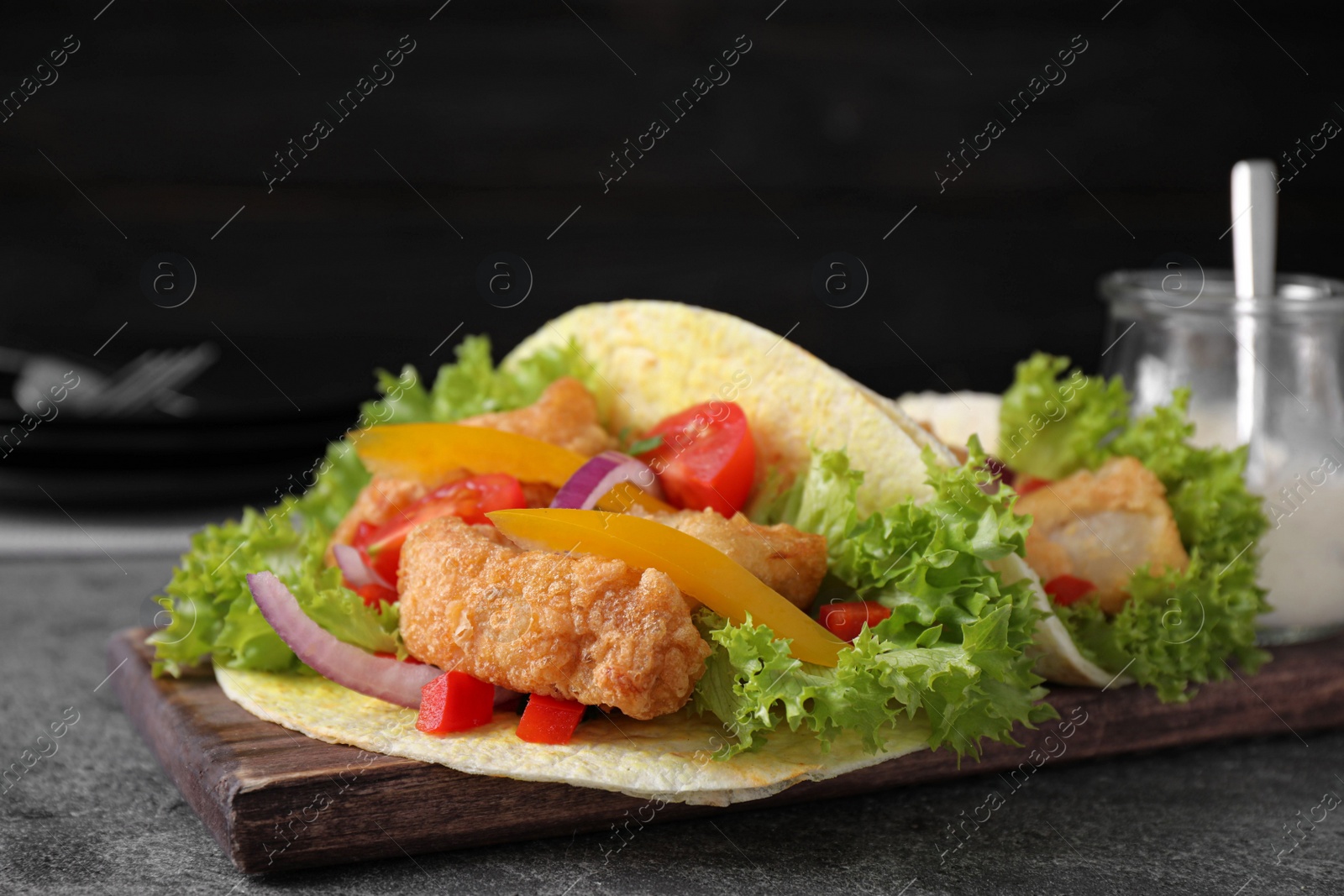 Photo of Delicious fish tacos served on grey table, closeup