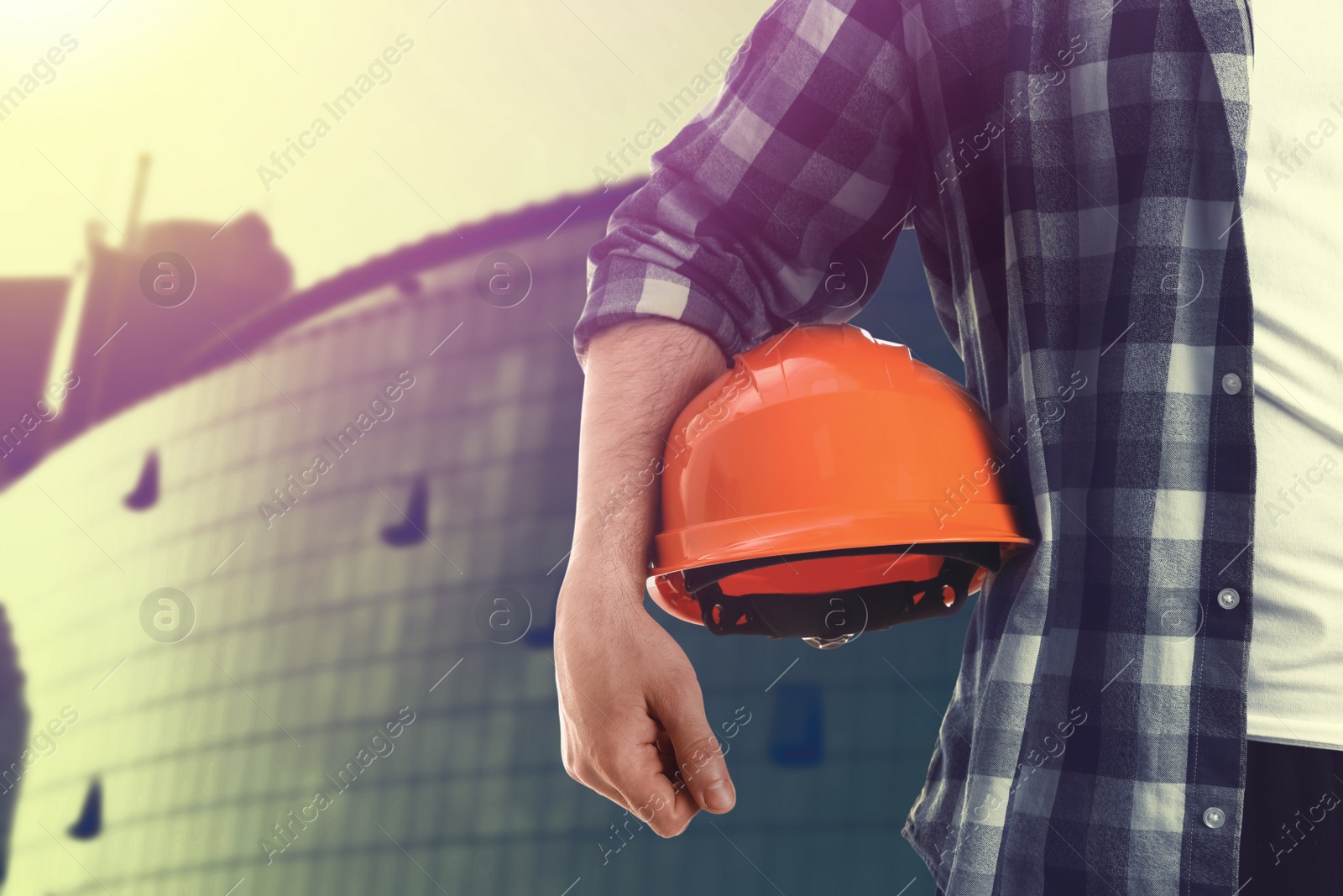 Image of Man with orange hard hat at construction site, closeup. Space for text 