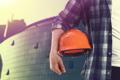 Image of Man with orange hard hat at construction site, closeup. Space for text 