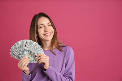 Photo of Happy young woman with cash money on pink background. Space for text