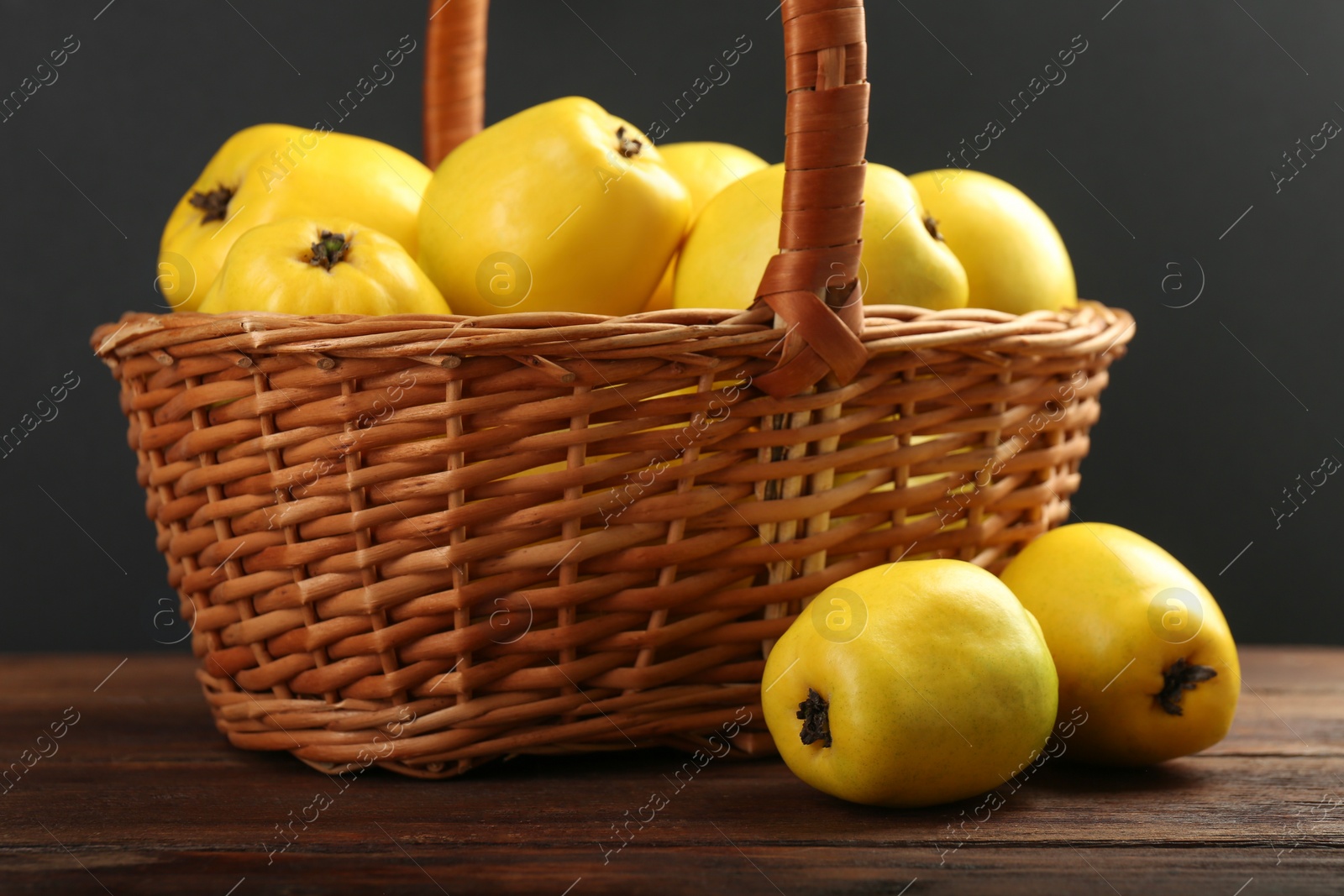 Photo of Basket with delicious ripe quinces on wooden table