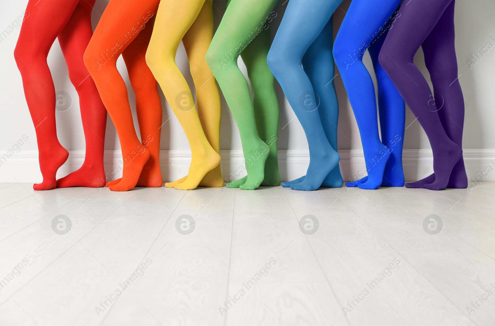 Photo of Women wearing colorful tights near white wall, closeup