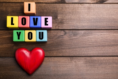 Photo of Colorful cubes with words I Love You and red heart on wooden background, flat lay. Space for text