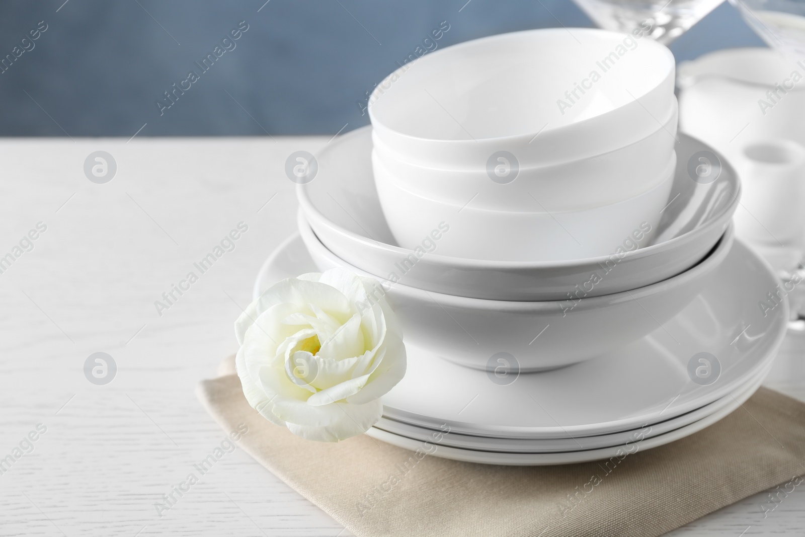 Photo of Dishware, napkin and eustoma flower on light table, space for text