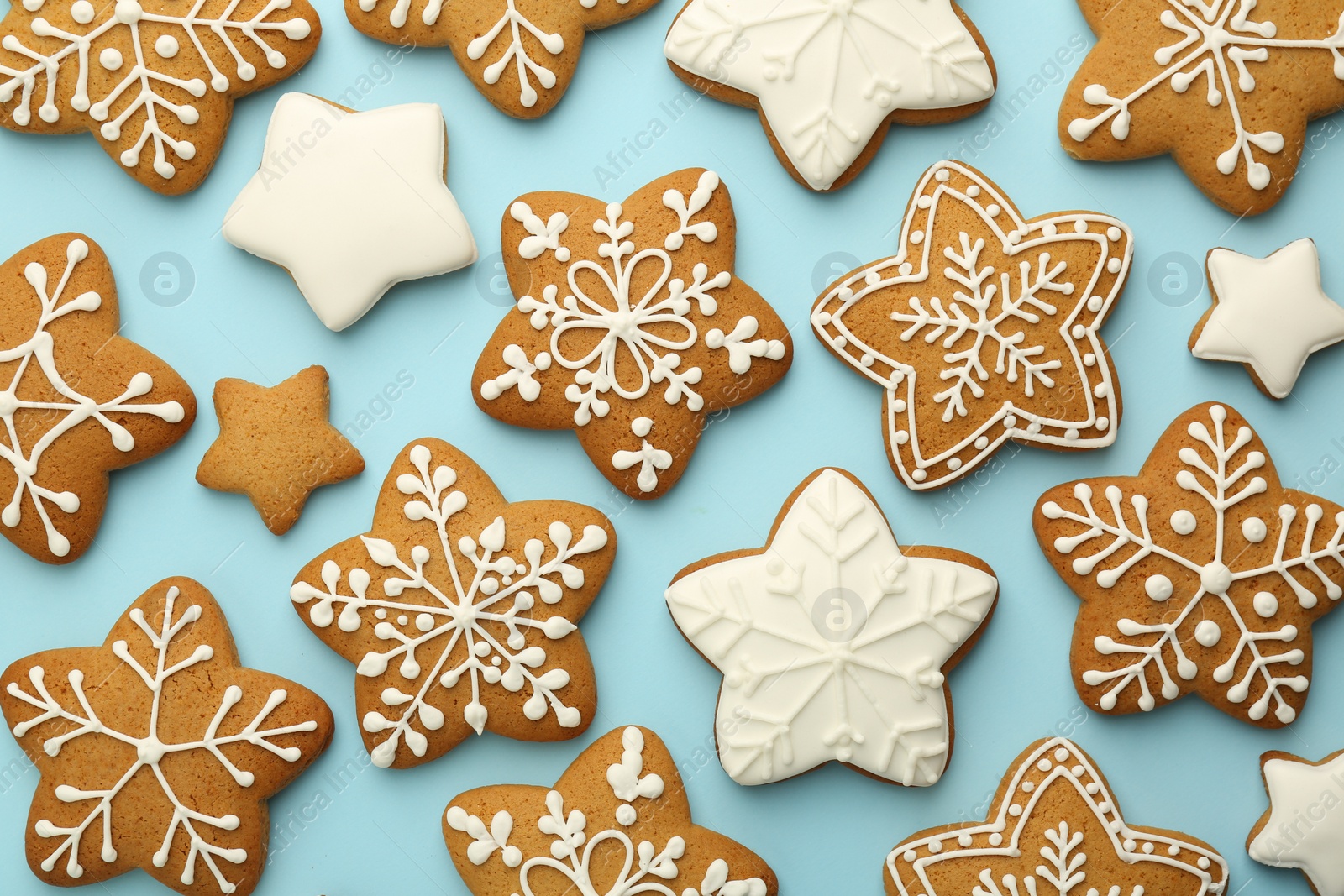 Photo of Tasty star shaped Christmas cookies with icing on light blue background, flat lay