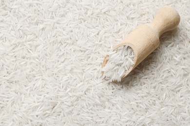 Photo of Raw basmati rice and scoop, top view. Space for text